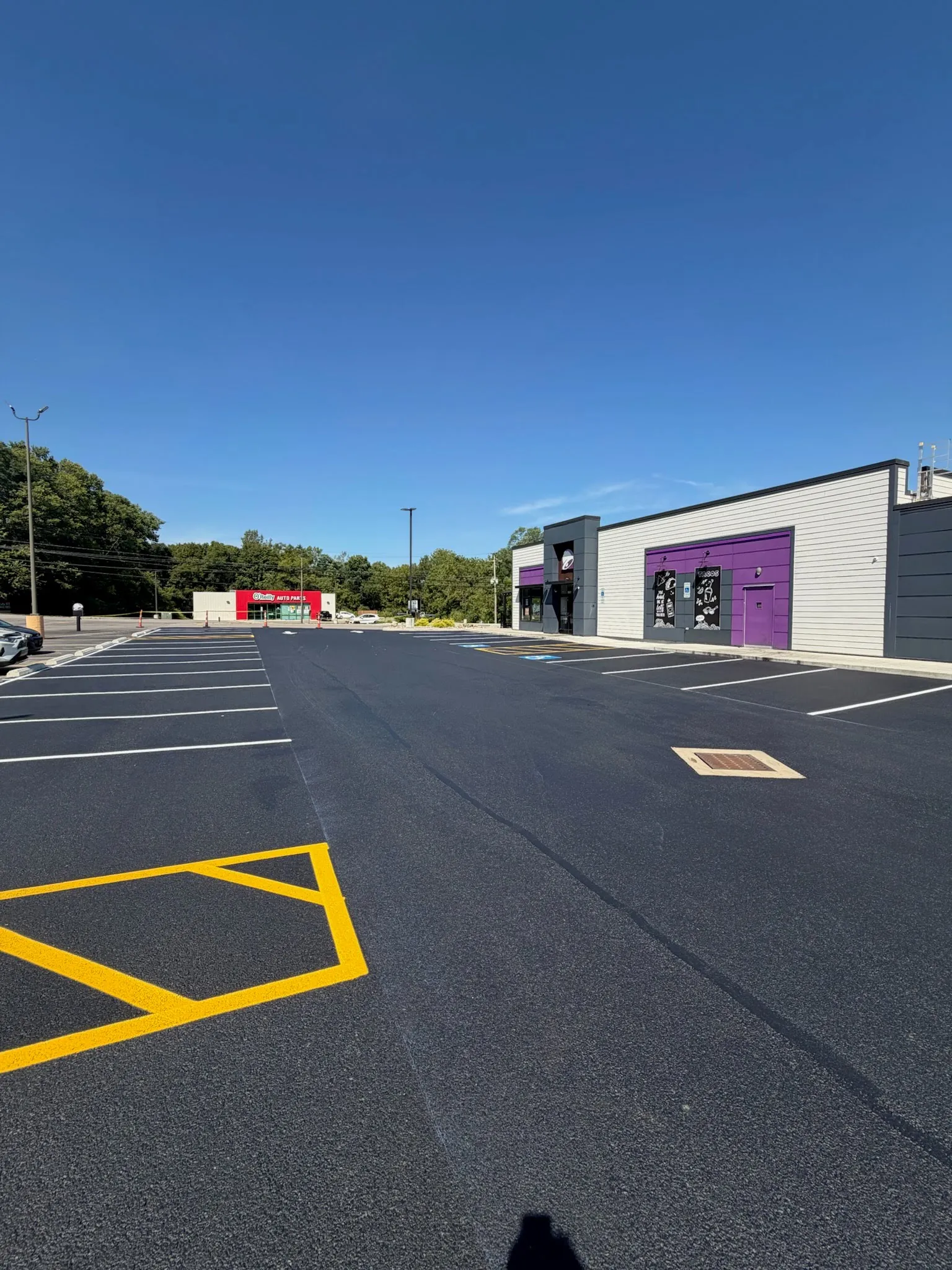 Freshly sealcoated commercial parking lot with new yellow accessible-parking striping and white lane lines
