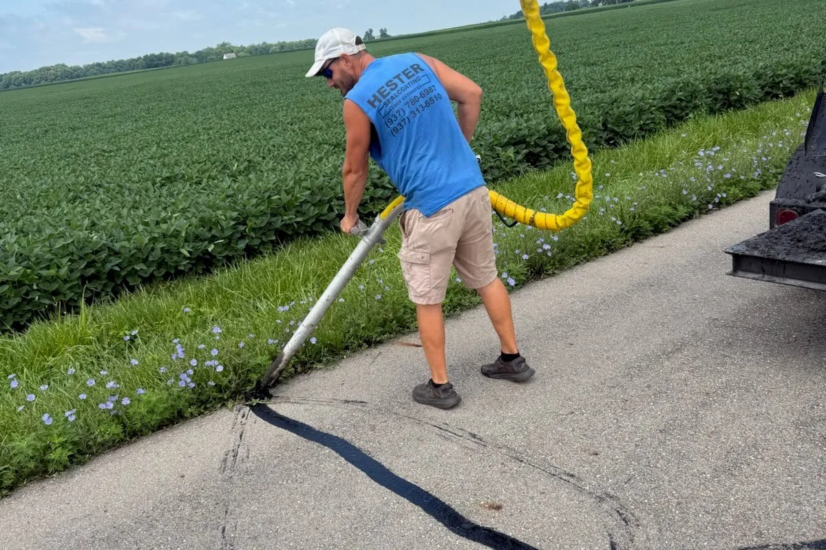 Hester Asphalt crew member applying hot rubberized sealant to a roadway crack